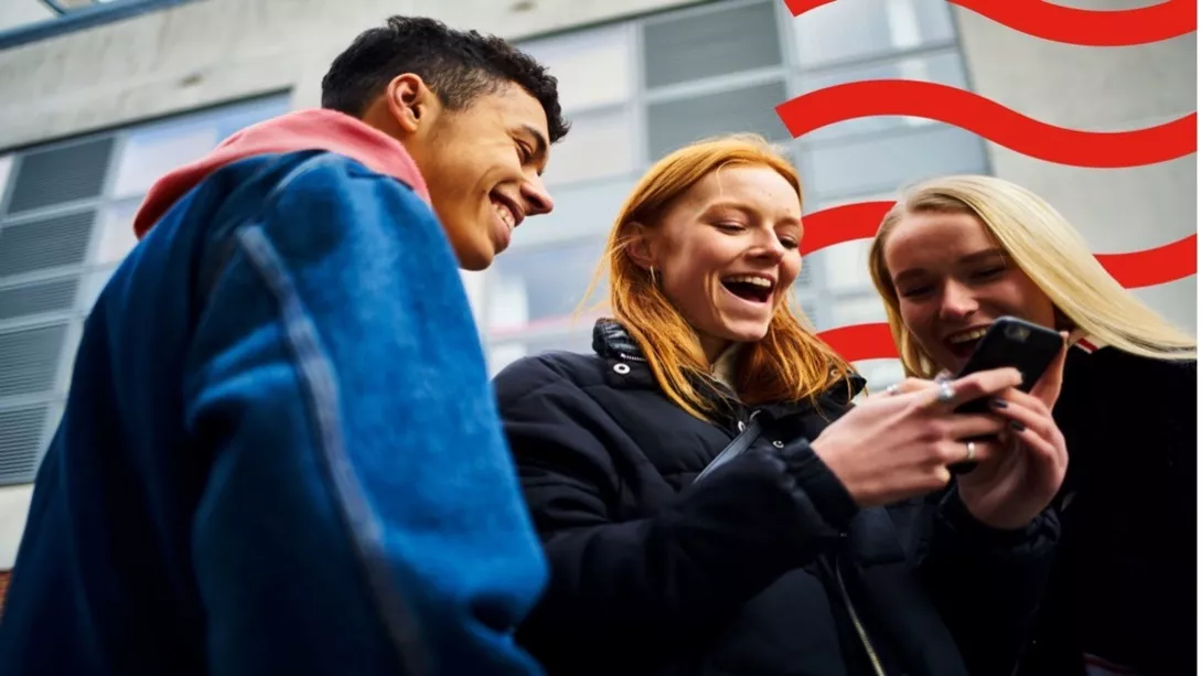 Three friends laughing while looking at the phone